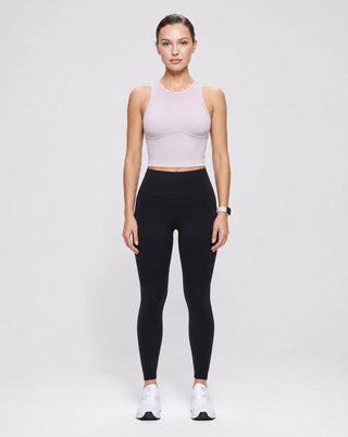 Women's pale pink ribbed crop tank top with fitted underbust seam detail, styled with black high-waisted leggings for gym workouts, Pilates, athleisure, and everyday activewear.
