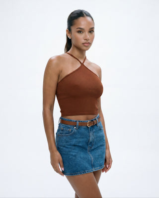 Women's rust brown seamless halter crop top with a crisscross neckline and ribbed knit fabric styled with a denim mini skirt
