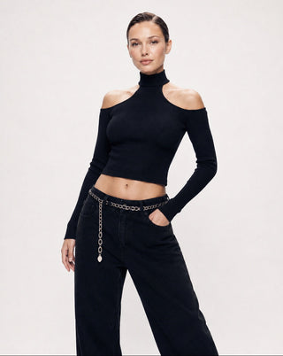 Black ribbed cold shoulder turtleneck crop top with long sleeves, styled with black wide leg jeans and a silver chain belt for a chic night out, city street style, dinner date, or elevated casual outfit.