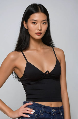 Woman wearing a black strappy top against a plain background