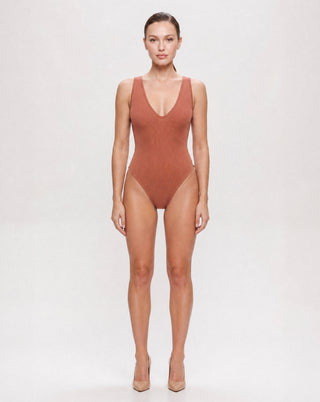 Women's rust ribbed sleeveless bodysuit with a deep V neckline and fitted silhouette, a versatile wardrobe essential for casual outfits, date nights, layering, and elevated everyday style.