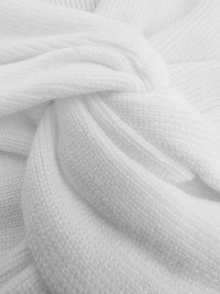 Detailed view of white ribbed stretch fabric featuring fine knit texture and soft premium material used in the women's long sleeve twist-front crop top