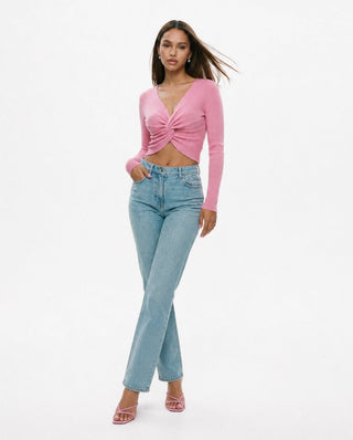 Women’s pink twist front long sleeve crop top paired with high-waisted light wash jeans and heels for a trendy going-out, brunch, weekend, and date night look