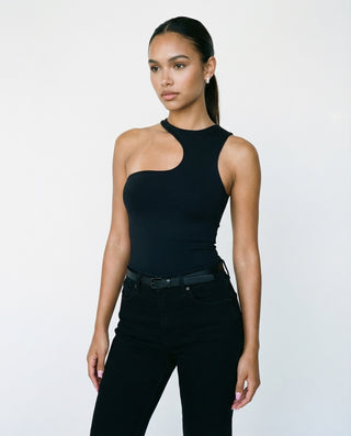 Women’s black asymmetrical sleeveless top styled on a model, featuring a one-shoulder neckline and sculpted fit against a white studio background.