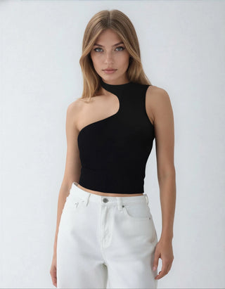Woman wearing a black one-shoulder top and white pants against a plain background