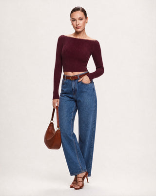 Women's wine red off the shoulder long sleeve crop top in soft ribbed knit fabric styled with high waisted straight leg jeans and a brown leather shoulder bag