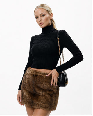 Women’s black ribbed turtleneck long sleeve crop top styled with a brown faux fur mini skirt and shoulder bag for a chic fall, winter, date night, and going-out outfit