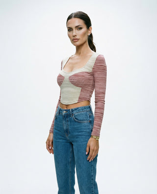 Women’s two-tone long sleeve crop top styled on a model, featuring a contrast panel design, scoop neckline, and fitted silhouette against a white studio background.