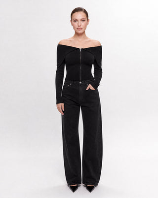 Women's black off-the-shoulder knit zip front crop top with a foldover neckline and long sleeves paired with wide leg denim for a modern elevated look