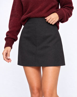 Close-up of women’s black high-waisted mini skirt with clean tailored silhouette and minimal seam detailing, a versatile fall wardrobe staple for casual, office and day-to-night outfits.
