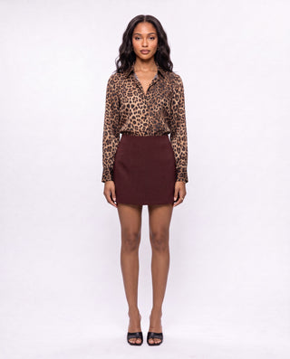 Women’s burgundy A-line mini skirt styled with a leopard print button-down blouse and black heels, a chic fall outfit for date nights, dinner, cocktails and weekend plans.