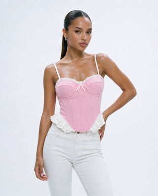 Women’s pink tweed corset bustier top with white ruffle trim, sweetheart neckline and bow detail, styled with white jeans for brunch, date night and feminine going-out looks.