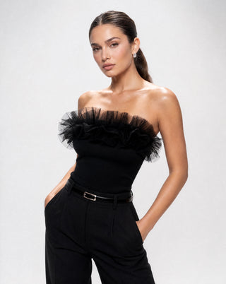 Women's black ruffle bandeau top with sheer tulle detailing, strapless neckline, and fitted silhouette paired with tailored trousers for a sophisticated outfit