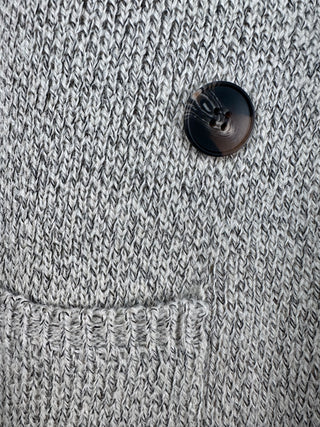 Close-up of women’s gray duster vest featuring black button details and tailored textured fabric, elevated modern outerwear for chic layered looks.