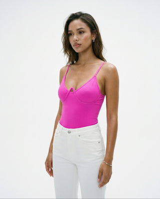 Women’s fitted hot pink camisole crop top styled on a model, featuring thin straps, a contoured bust seam, and a smooth, sculpted silhouette against a white studio background.