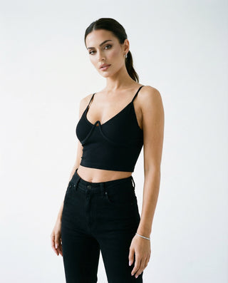 Women’s fitted camisole crop top styled on a model, featuring thin straps, a sculpted bust seam, and a sleek silhouette against a white studio background.
