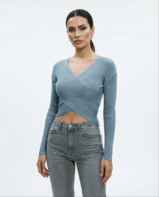 Model in a slate blue ribbed long sleeve crop top with a wrap-style front and deep V neckline, styled with high-waisted gray denim.