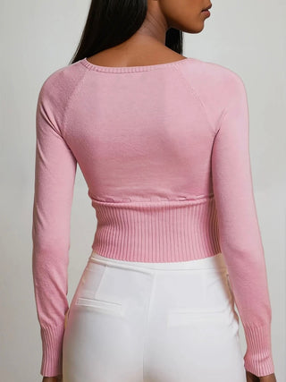 Person wearing a pink ribbed sweater against a plain background