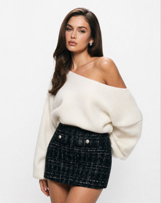 Women’s black tweed mini skirt with pearl button details, styled with an ivory off-the-shoulder sweater for a chic date night, holiday party, dinner, and elevated fall or winter outfit