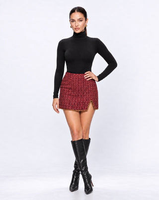 Women’s burgundy tweed mini skirt with gold chain trim and side slit, styled with a black turtleneck and knee-high boots for chic fall outfits, holiday parties, date nights and city style.