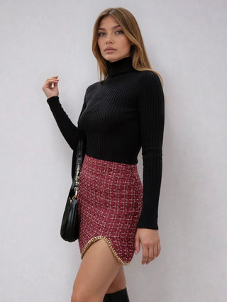 Woman wearing a black turtleneck and patterned skirt with knee-high boots on a white background