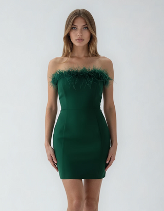 Woman wearing a green strapless dress with feather details on a white background
