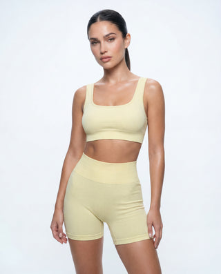 Women's pastel yellow seamless gym set with a ribbed sports bra and high-waisted biker shorts for yoga, workouts, and athleisure styling