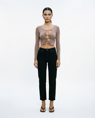 Women’s long sleeve cutout crop top styled on a model, featuring a ruched front detail and fitted silhouette against a white studio background.