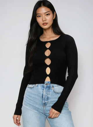 Woman wearing a black long-sleeve top with cut-out design and light blue jeans on a white background