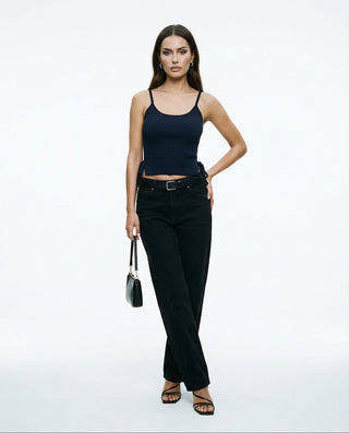 Model wearing a black ribbed crop top with thin spaghetti straps and a fitted silhouette, styled with high-waisted black jeans against a clean white background.