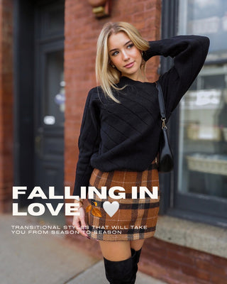 New arrivals collection header. Model wearing a black loose fitting sweater and a camel colored plaid mini skirt while holding a black bag.