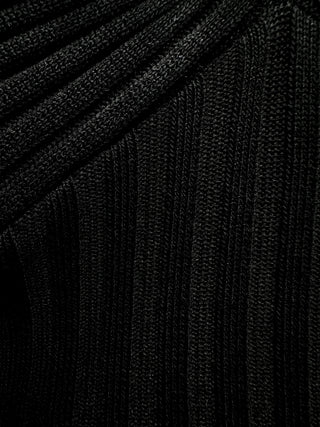 A fabric shot of a black knot halter crop top with thick ribbed material, featuring a knot detail on the chest and a frilled bottom seam.