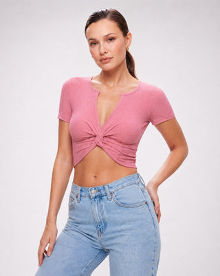 Women's dusty pink ribbed twist front crop top with a deep V-neckline, short sleeves, fitted silhouette, and soft stretch fabric styled with light wash high waisted jeans