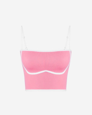 Front product image of a pink ribbed bralette style crop top with white contrast edging, curved bust seam shaping, and delicate spaghetti straps.
