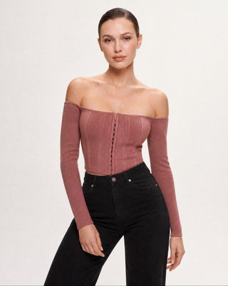 Women's dusty rose long sleeve off-the-shoulder corset top with a structured fit and front hook closure paired with black denim for an elevated casual look