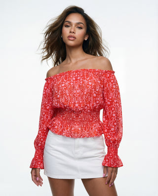 Model wearing a red floral off-the-shoulder chiffon crop top with smocked waist and long sleeves, styled with a white mini skirt