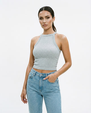 Women’s sleeveless halter crop top styled on a model, featuring a high neckline, fitted silhouette, and soft ribbed fabric against a white studio background.