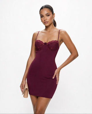 Women’s burgundy lace bustier mini dress with spaghetti straps and fitted bodycon silhouette, styled with a nude clutch for a chic date night, cocktail party, wedding guest, and going-out look
