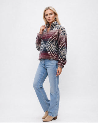 Women’s southwestern tribal print fleece pullover in burgundy, cream, and navy with quarter zip collar and relaxed fit, styled with light wash straight leg jeans and ankle boots in a studio setting.