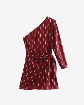 Burgundy one-shoulder mini dress shown from the front, featuring a long sleeve, wrap-style skirt, asymmetrical neckline, and all-over geometric print.