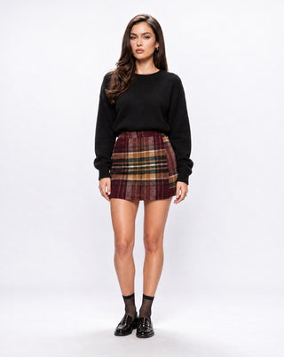 Women’s burgundy plaid pleated mini skirt styled with an oversized black sweater, sheer socks and loafers, a chic fall outfit for city days, brunch, coffee runs and casual weekend plans.
