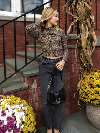 Woman wearing leopard skin long sleeve ruched top.