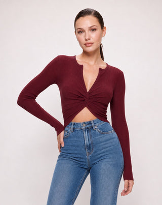 Women's wine red ribbed twist front crop top with long sleeves, flattering V-neck, and front cutout for an elevated everyday look paired with denim jeans