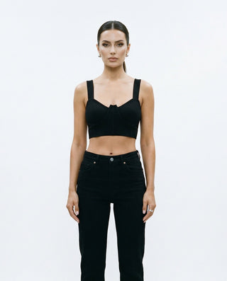 Women’s fitted brami top featuring wide shoulder straps, structured bust detailing, and a cropped silhouette, styled on a model against a white studio background.
