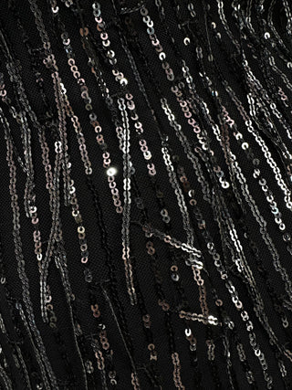 Close-up detail of a black sequin mini dress for women showing densely packed shimmering sequins, textured surface, and light-reflective finish.