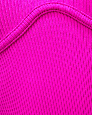 Close-up of hot pink ribbed knit fabric showcasing the soft stretch texture, fine vertical ribbing, and premium quality construction of the women's mock neck bodysuit